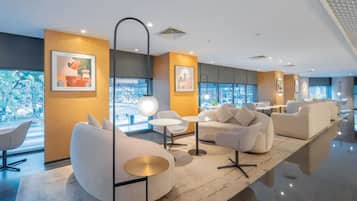 A modern lounge area with seating, artwork, and large windows.