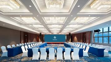 A conference room with a long table, white chairs, and chandeliers.