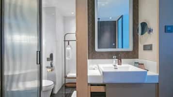 A modern bathroom with a glass shower enclosure, a white toilet, a sink with a mirror, and a towel rack.