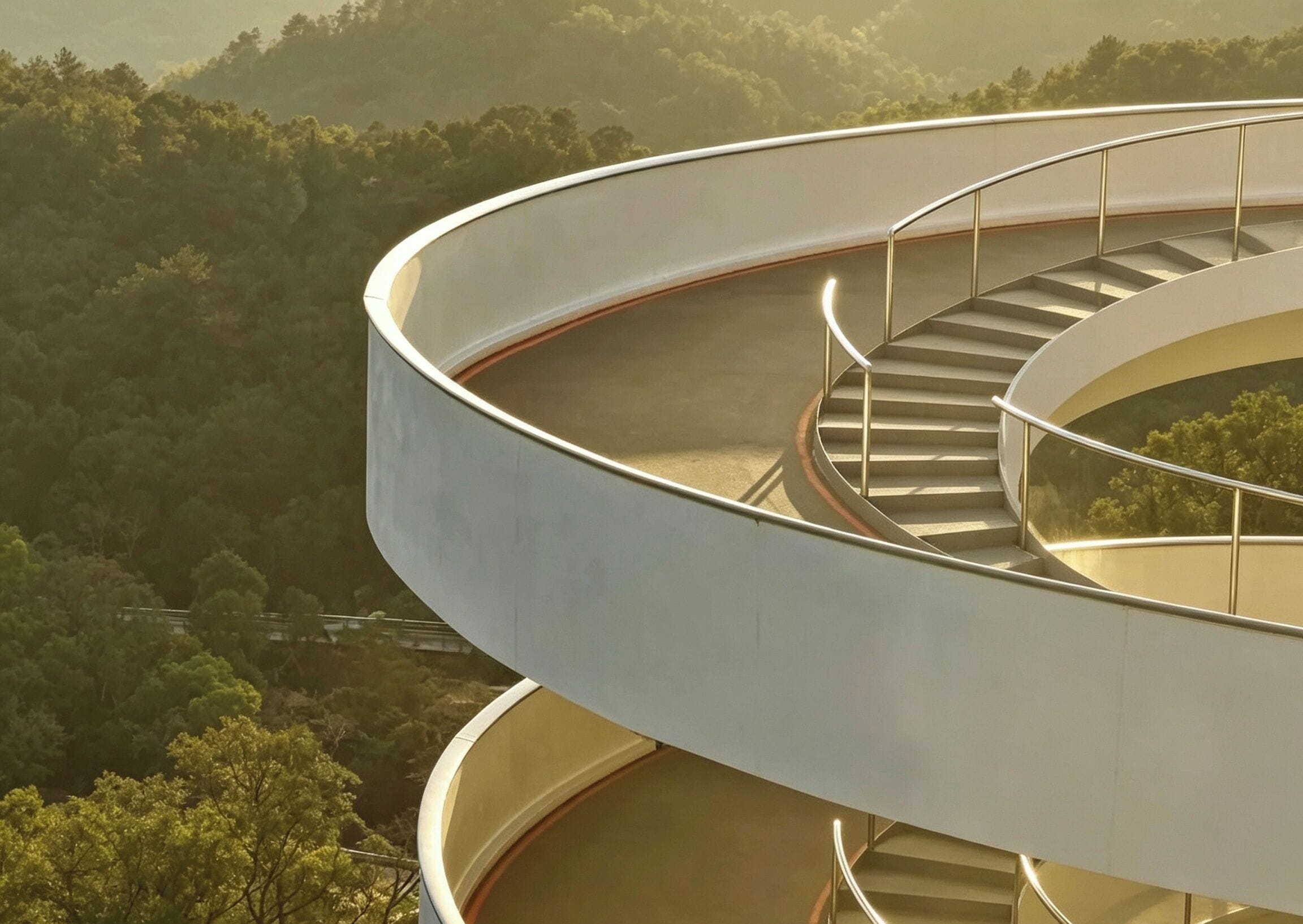 A spiral staircase with a glass enclosure, surrounded by a forested landscape.