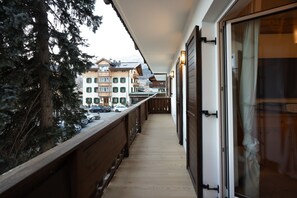 A wooden balcony with a view of parked cars and buildings in the background. - Casa Ampezzo, in the town center with balcony and parking area (Cortina d´Ampezzo)