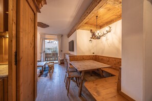 A wooden interior with a large bench, a dining table, and a chandelier. - Casa Ampezzo, in the town center with balcony and parking area (Cortina d´Ampezzo)