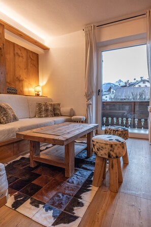 A cozy living room with a wooden coffee table, a sofa, and a patterned rug. - Casa Ampezzo, in the town center with balcony and parking area (Cortina d´Ampezzo)