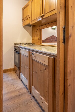 A kitchen with wooden cabinets, a stove, and a countertop. - Casa Ampezzo, in the town center with balcony and parking area (Cortina d´Ampezzo)