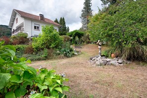 Une maison avec un jardin, une statue et une vue sur une colline.