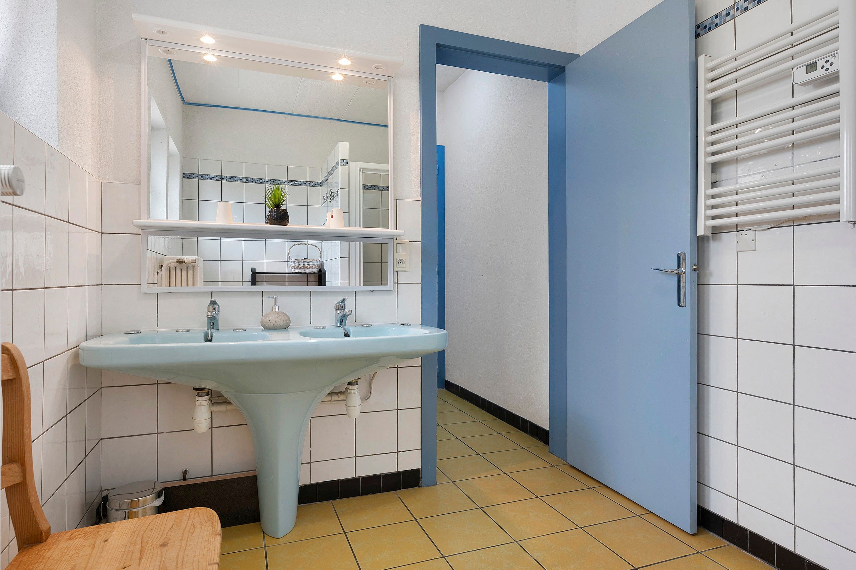 Une salle de bain avec un lavabo, un miroir et un porte-serviettes.