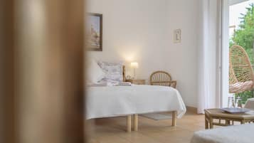 Une chambre à coucher avec un lit, une table de chevet, une lampe, une chaise et une vue sur la verdure par la fenêtre.