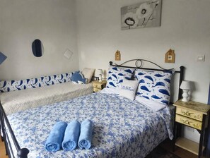 A double bed with floral bedding, two pillows with a blue whale pattern, and a pair of rolled towels.