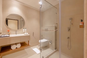A modern bathroom with a glass-enclosed shower, a sink with toiletries, and a mirror.