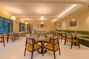 A restaurant with multiple tables and chairs, large windows, and artwork on the walls.