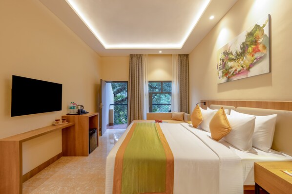 A hotel room with a bed, a flat-screen TV, a desk, and a window with curtains.