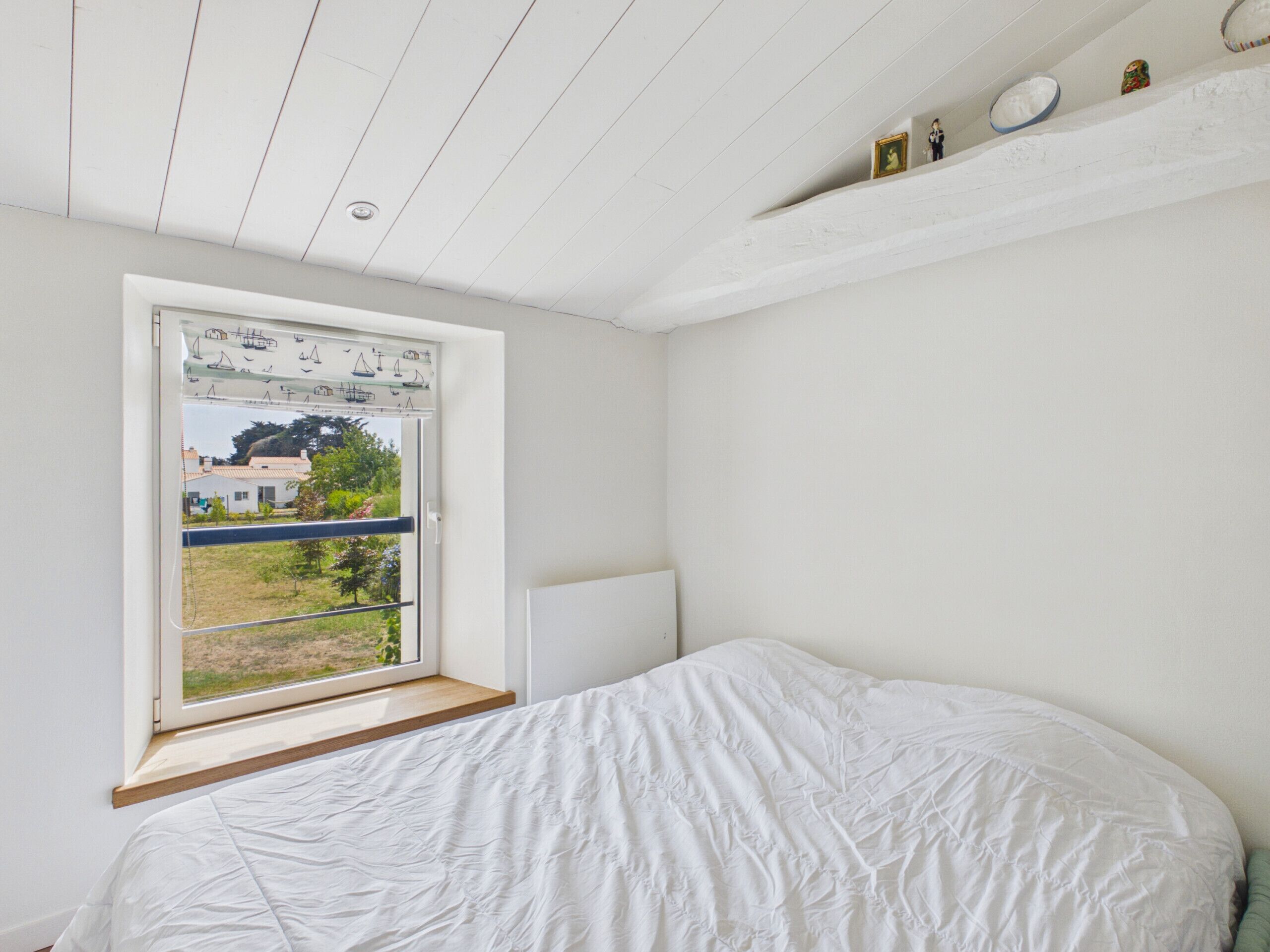 Une chambre avec un lit simple, une fenêtre donnant sur l’extérieur et un plafond blanc.