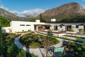 A modern house with a patio area, surrounded by a garden with a gravel path. - 6 on Heide (Franschhoek)