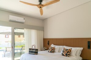 A hotel room with a bed, a ceiling fan, an air conditioning unit, a sliding glass door to a balcony, and a bag on the bed. - 6 on Heide (Franschhoek)