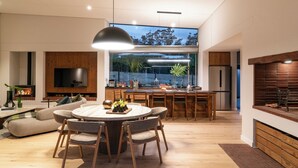 A modern kitchen with a dining area, large windows, and a flat-screen TV. - 6 on Heide (Franschhoek)