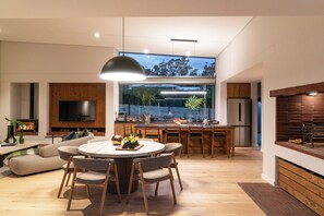 A modern kitchen with a dining area, large windows, and a flat-screen TV. - 6 on Heide (Franschhoek)
