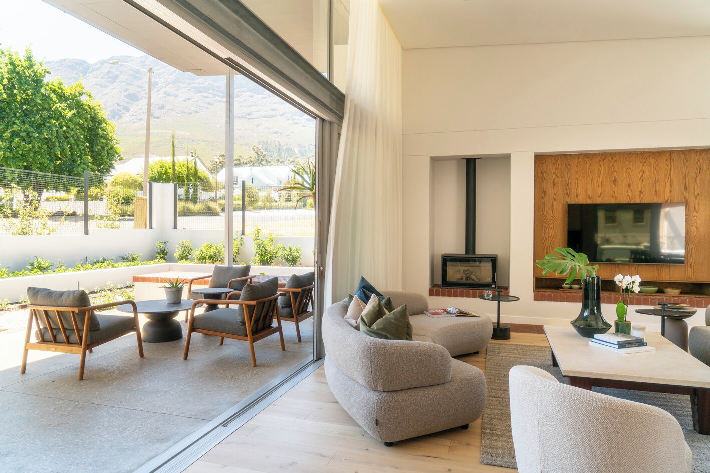 A modern living room with a sofa, chairs, a TV, and a fireplace.