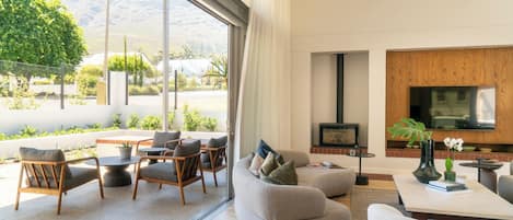 A modern living room with a sofa, chairs, a TV, and a fireplace.