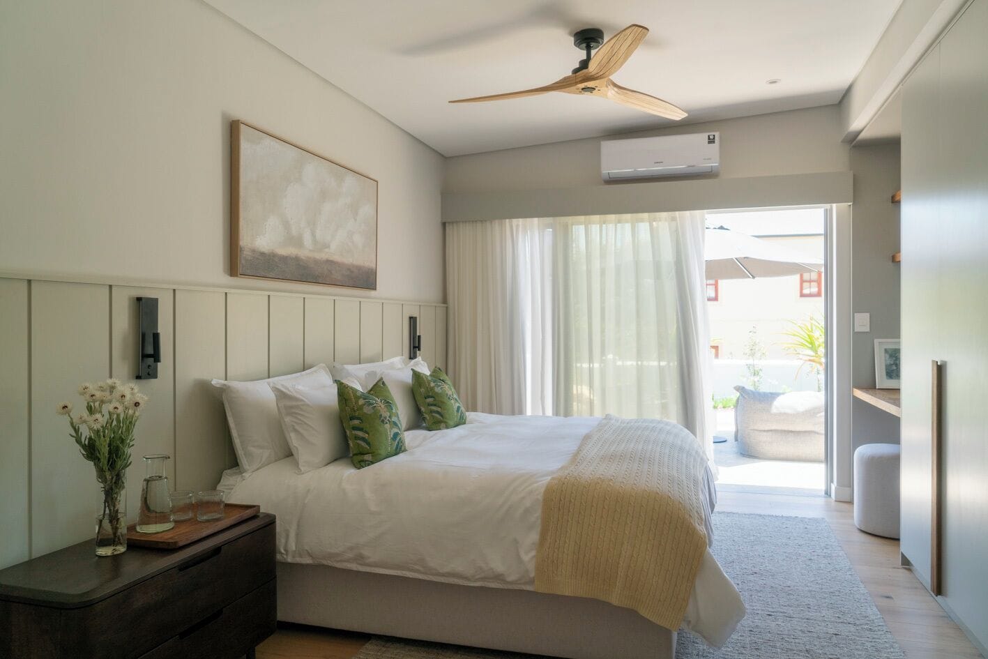 A bedroom with a bed, bedside table, nightstand, and a ceiling fan.