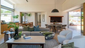 A modern living room with a sofa, coffee table, and dining area. - 6 on Heide (Franschhoek)