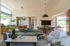 A modern living room with a sofa, coffee table, and dining area. - 6 on Heide (Franschhoek)