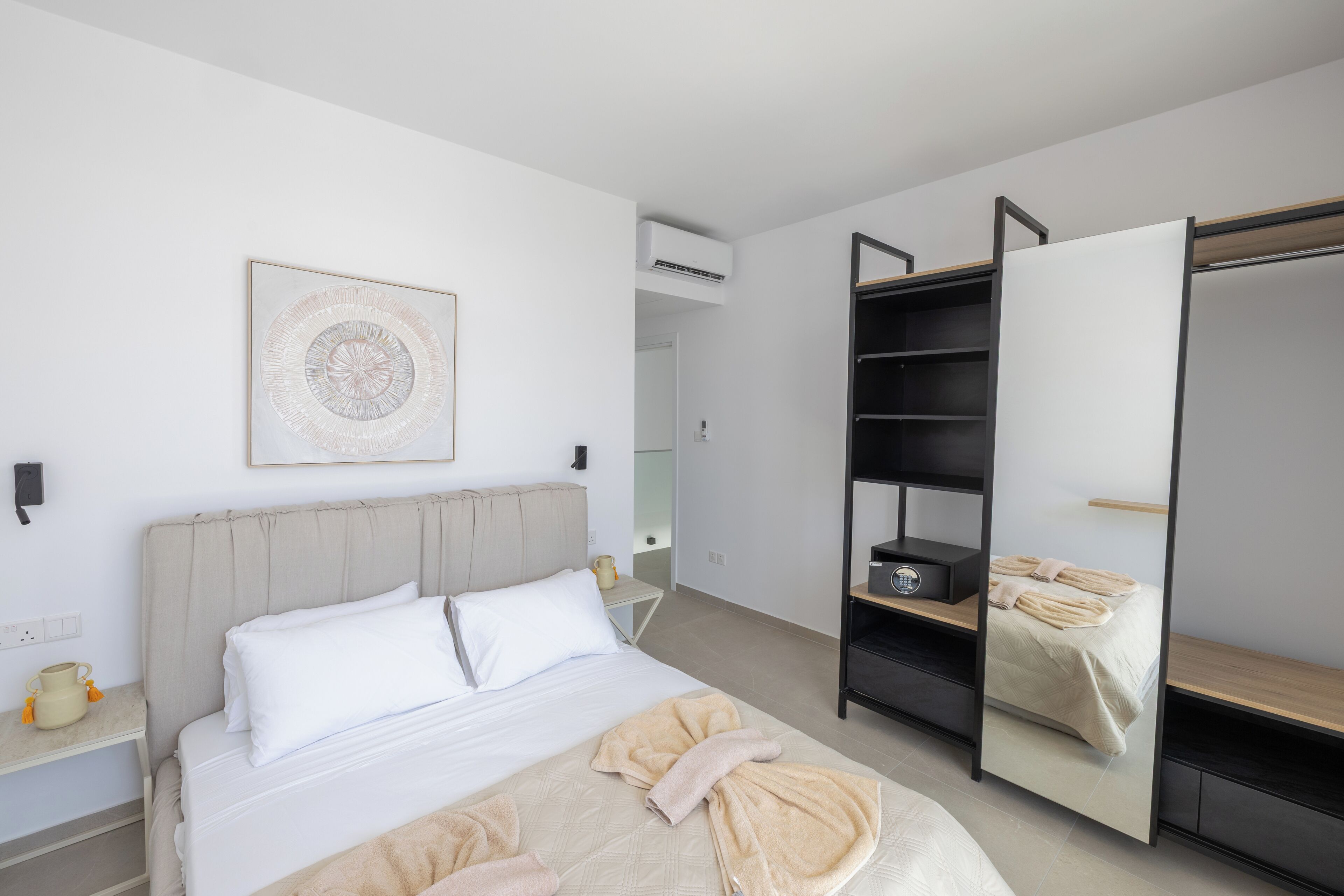 A modern bedroom with a bed, bedside table, and a wardrobe with a mirror.