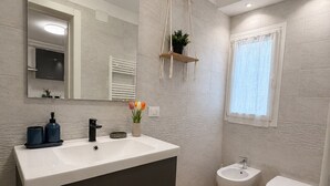 A modern bathroom with a large mirror, a vanity with a sink, a bidet, and a toilet. - Cozy apartment 10-minute bus ride from the heart of Venice (Venezia)