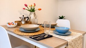 A dining table set with plates, bowls, cutlery, and a vase with flowers. - Cozy apartment 10-minute bus ride from the heart of Venice (Venezia)
