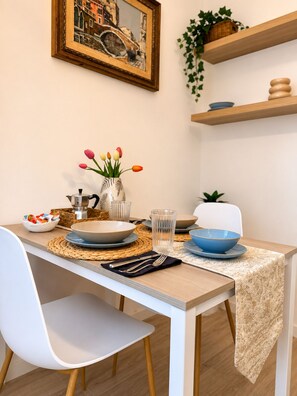 Ein Esstisch gedeckt mit Tellern, Schüsseln, Besteck und einer Blumenvase.