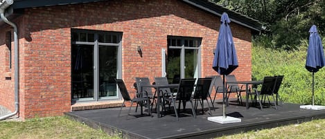 A brick building with a patio area featuring a table and chairs, and two umbrellas.