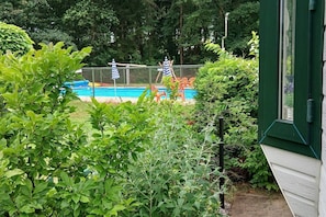 A fenced outdoor area with a pool, surrounded by lush greenery.