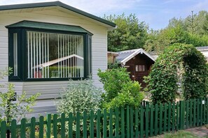 A single-story house with a bay window, a wooden door, and a green picket fence.