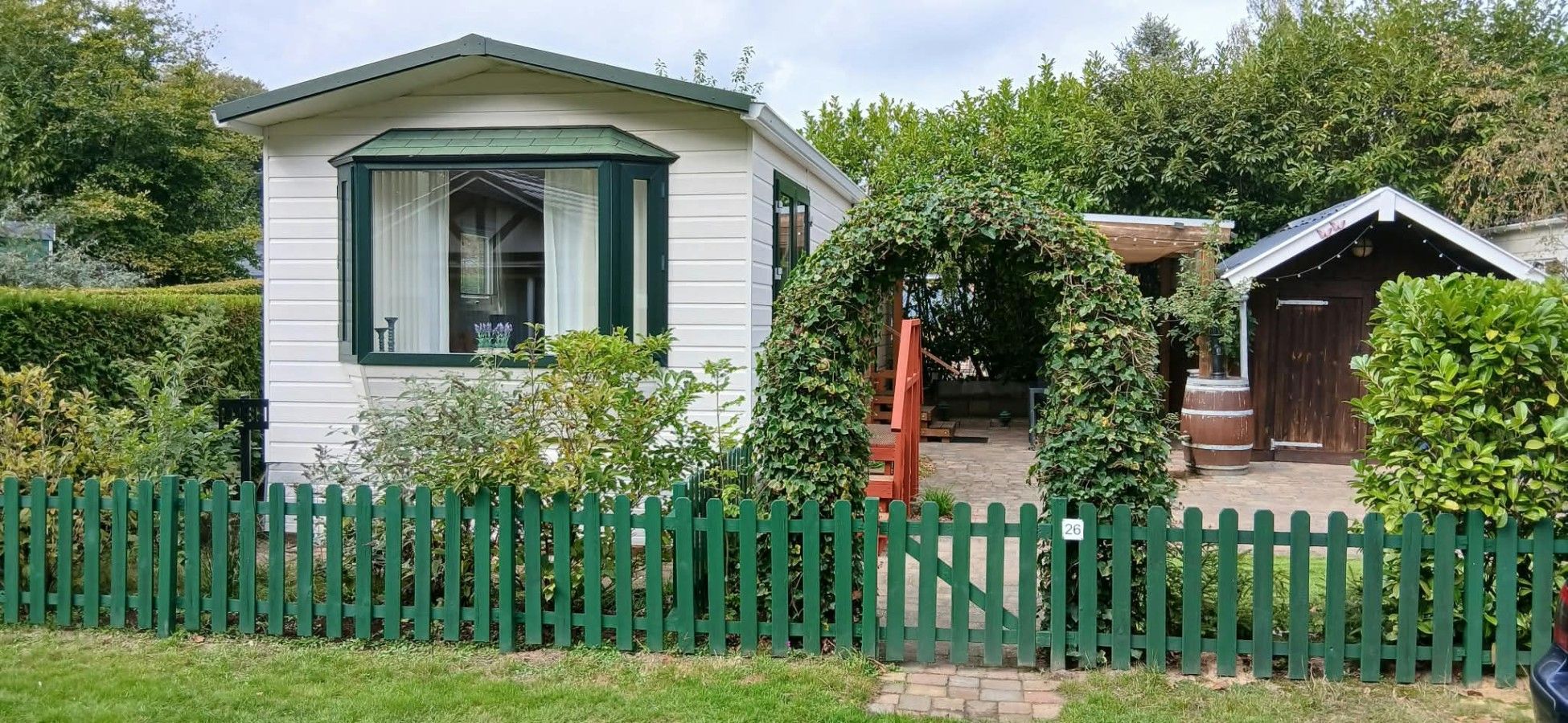 A white building with a green roof and a white fence.