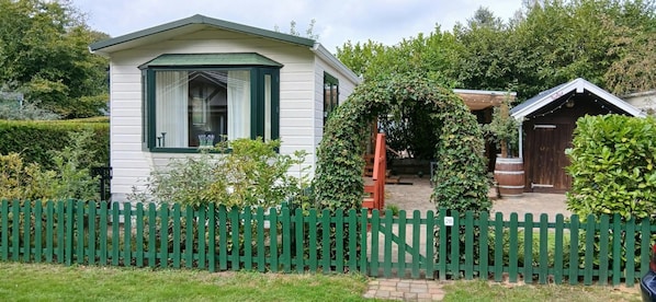 A white building with a green roof and a white fence.