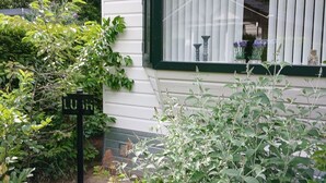 Een huis met een raam, een bord en omliggende beplanting.