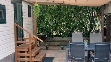 Une terrasse avec un escalier en bois, une table avec des chaises et une plante suspendue.