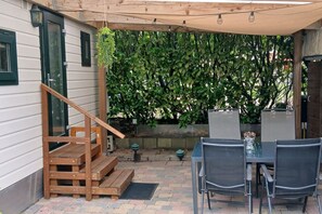 A patio with a wooden staircase, a table with chairs, and a hanging plant.