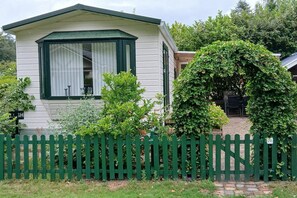 Ein Wohnmobil mit grünem Zaun, einer Veranda und einem kleinen Garten.