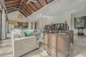 A spacious living area with a high ceiling, a sofa set, a coffee table, and a television.