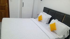 Una cama con una colcha acolchada blanca y dos almohadas, una con detalle amarillo.