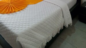 Habitación de hotel con una cama, dos almohadas, un adorno naranja y vistas por una ventana.