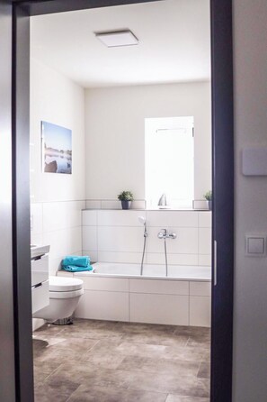 Een moderne badkamer met toilet, wastafel en douche.
