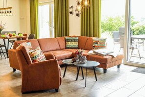 A modern living room with a brown leather sofa, a coffee table, and decorative pillows. - SEEside13. Lake view. Sauna. Front Row at Diemelsee (Diemelsee)