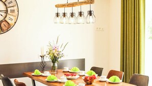 A dining area with a wooden table, black chairs, a hanging light fixture, and a clock on the wall. - SEEside13. Lake view. Sauna. Front Row at Diemelsee (Diemelsee)
