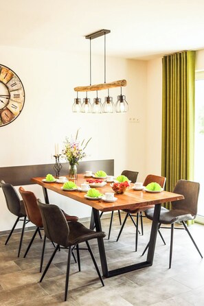 A dining area with a wooden table, black chairs, a hanging light fixture, and a clock on the wall. - SEEside13. Lake view. Sauna. Front Row at Diemelsee (Diemelsee)