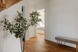 A hallway with a wooden bench, a potted plant, and a bed in the background. - Hildes Huuske | Right on the Water - Outdoor Sauna (Greetsiel)