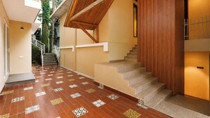 A staircase with a wooden handrail and patterned floor tiles leading to a second-floor landing.