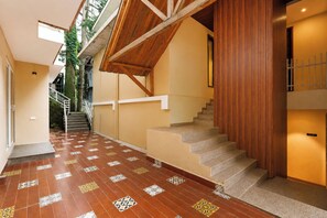 A staircase with a wooden handrail and patterned floor tiles leading to a second-floor landing.