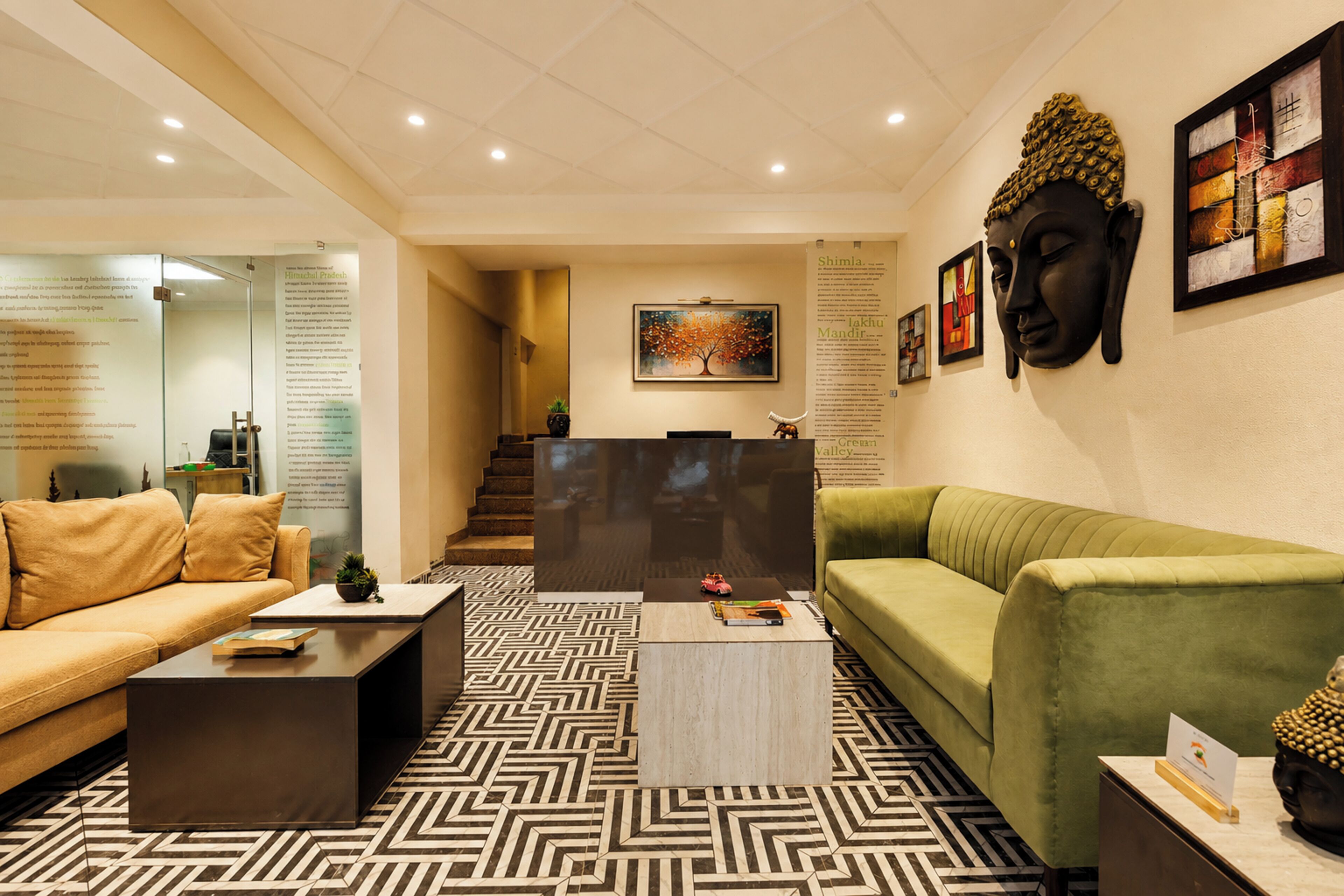 Un área de recepción moderna con un sofá, una mesa de centro y una estatua de Buda.