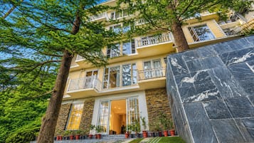 Un edificio de varios pisos con balcones, fachada de piedra y césped bien cuidado.